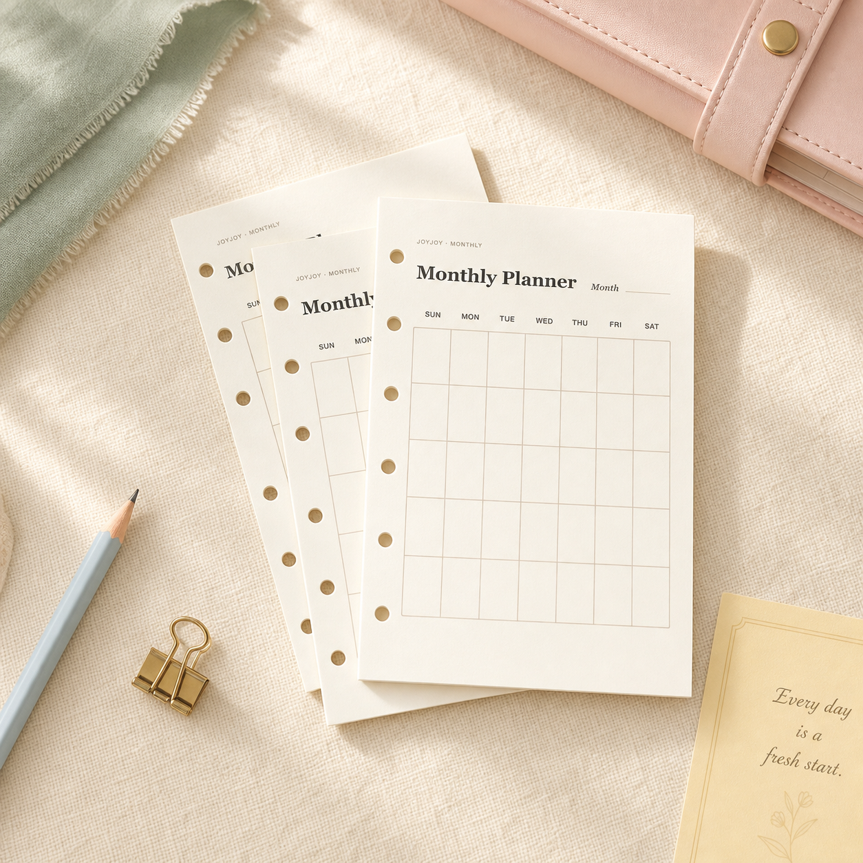 JoyJoy A7 monthly planner inserts with six evenly spaced holes on a warm cream background