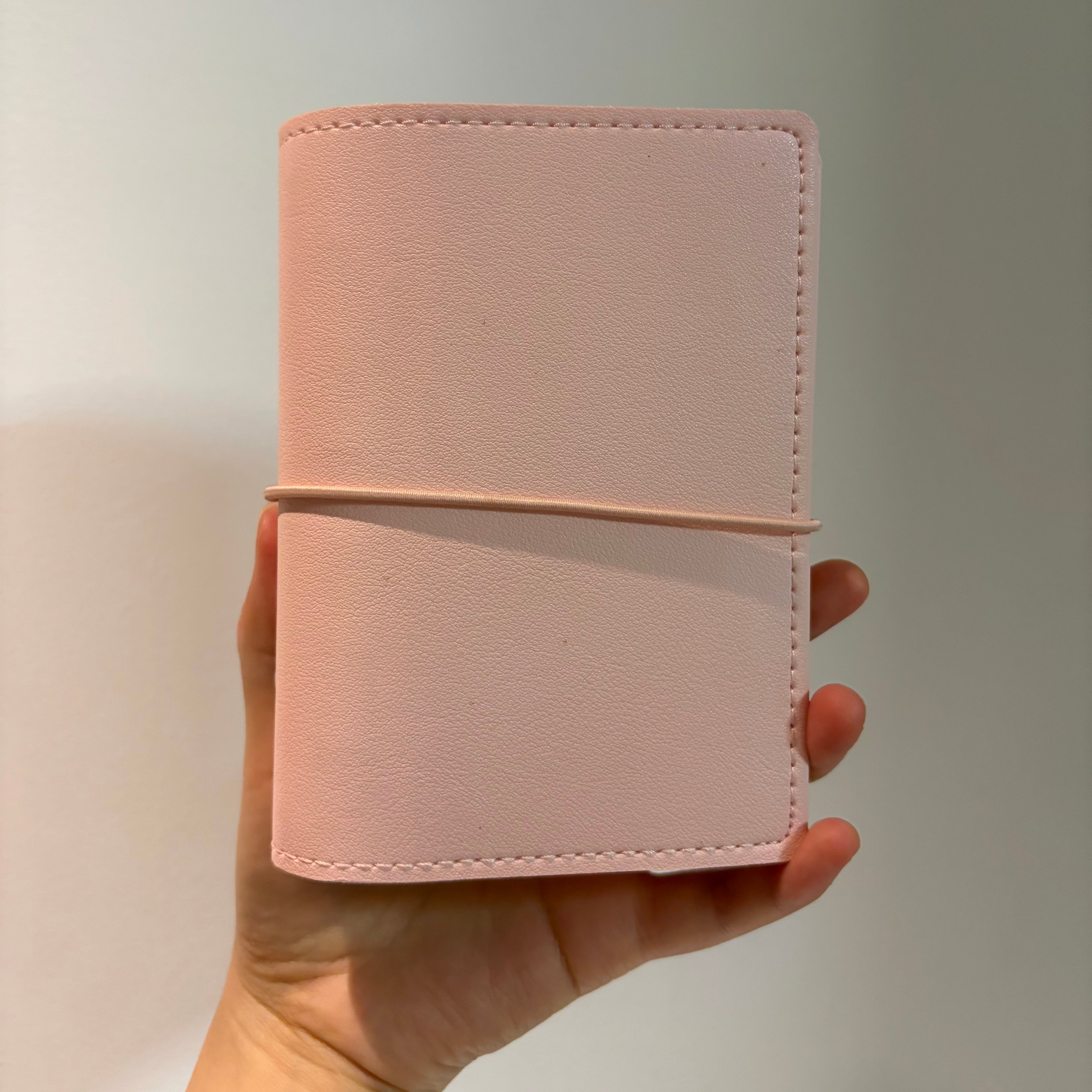 Woman holding an aesthetic A7 soft blush pink binder cover in her hand