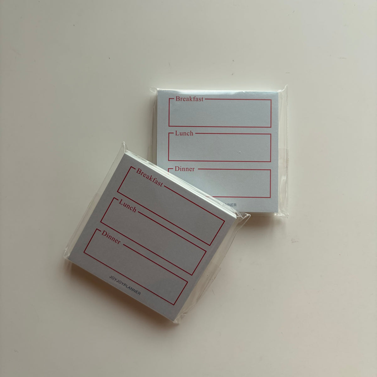 Real photo of two packaged Daily Meal Log mini memo pads with breakfast, lunch and dinner boxes