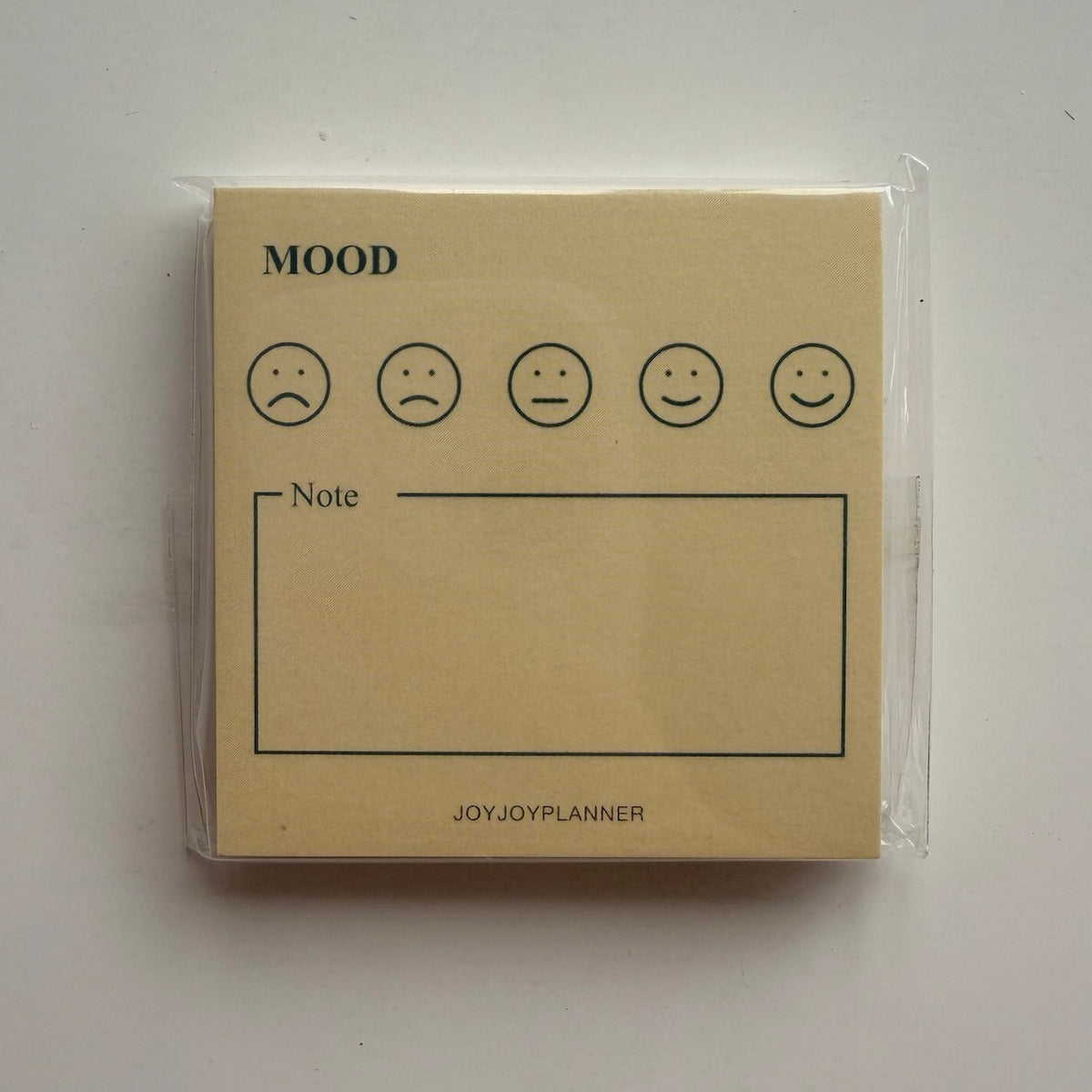Real photo of the packaged Daily Mood Tracker mini memo pad with five mood faces and a note box