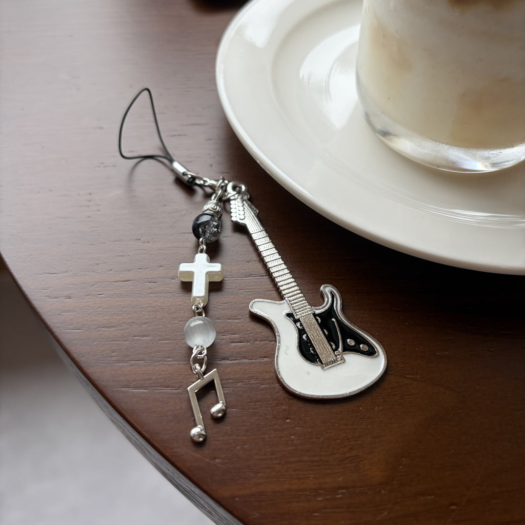 Black guitar beaded phone charm styled on a coffee table