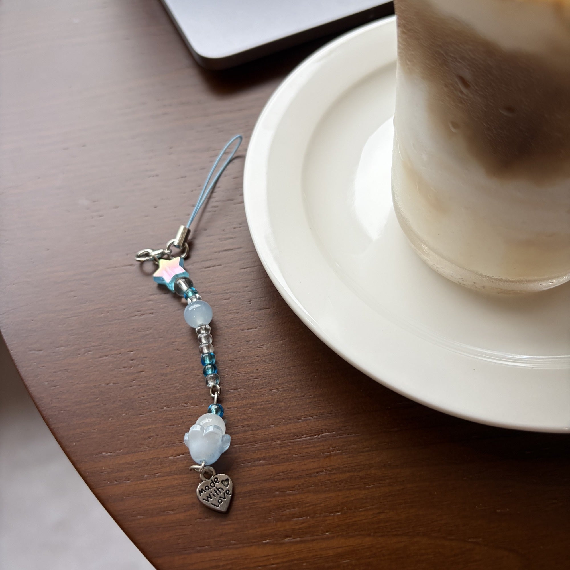 Sea Salt Moon blue beaded phone and planner charm close detail on a cafe table
