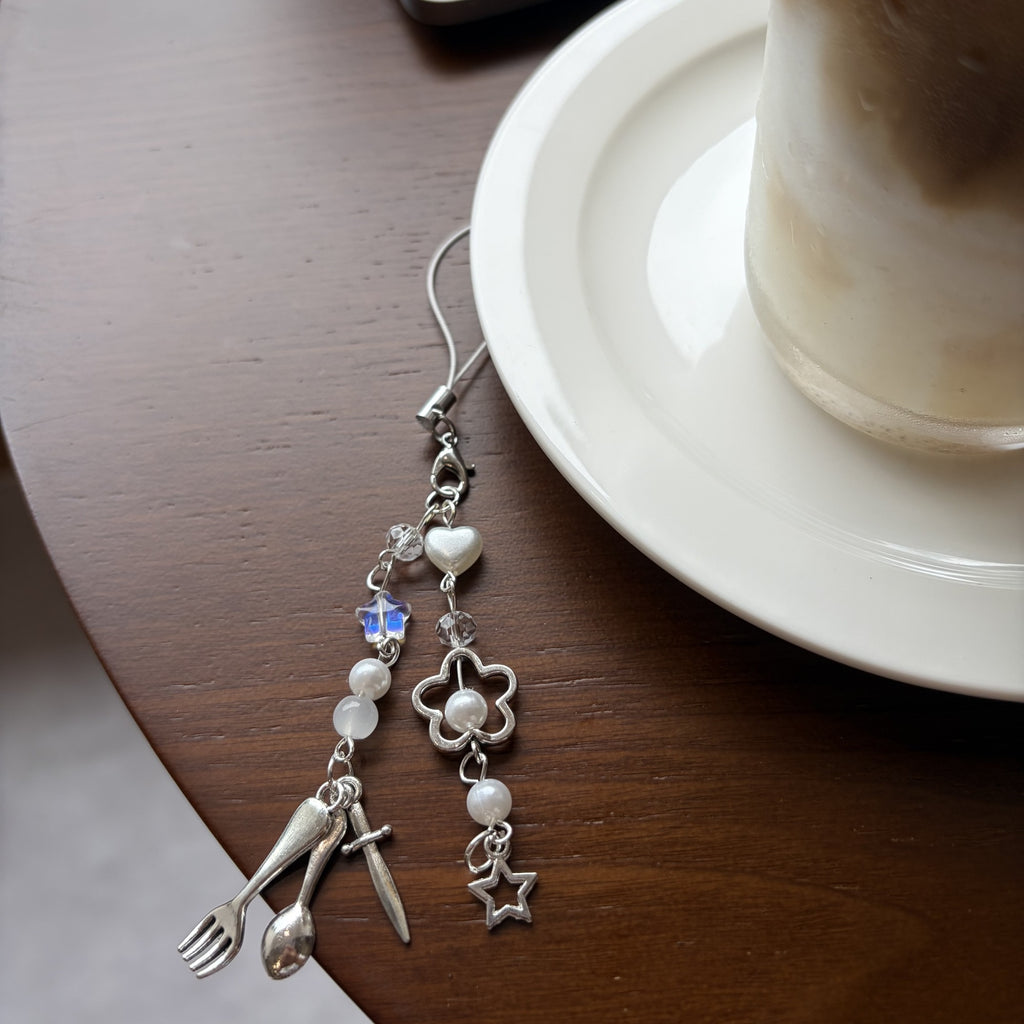 Fork spoon knife planner charm with pearl beads on a cafe table