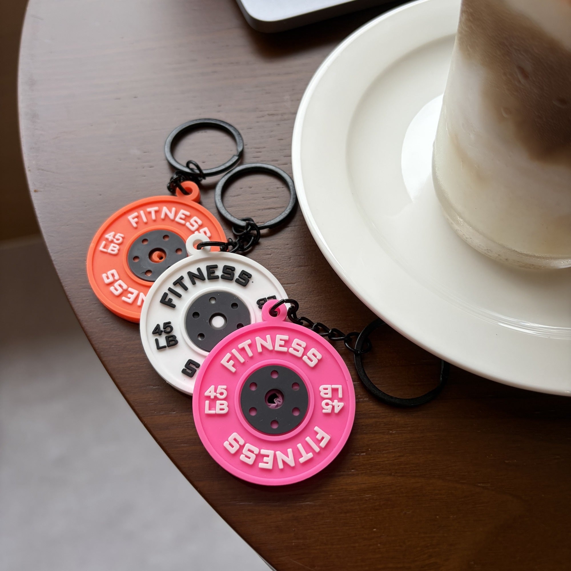 Mini weight plate planner charms in orange white and pink styled on a cafe table