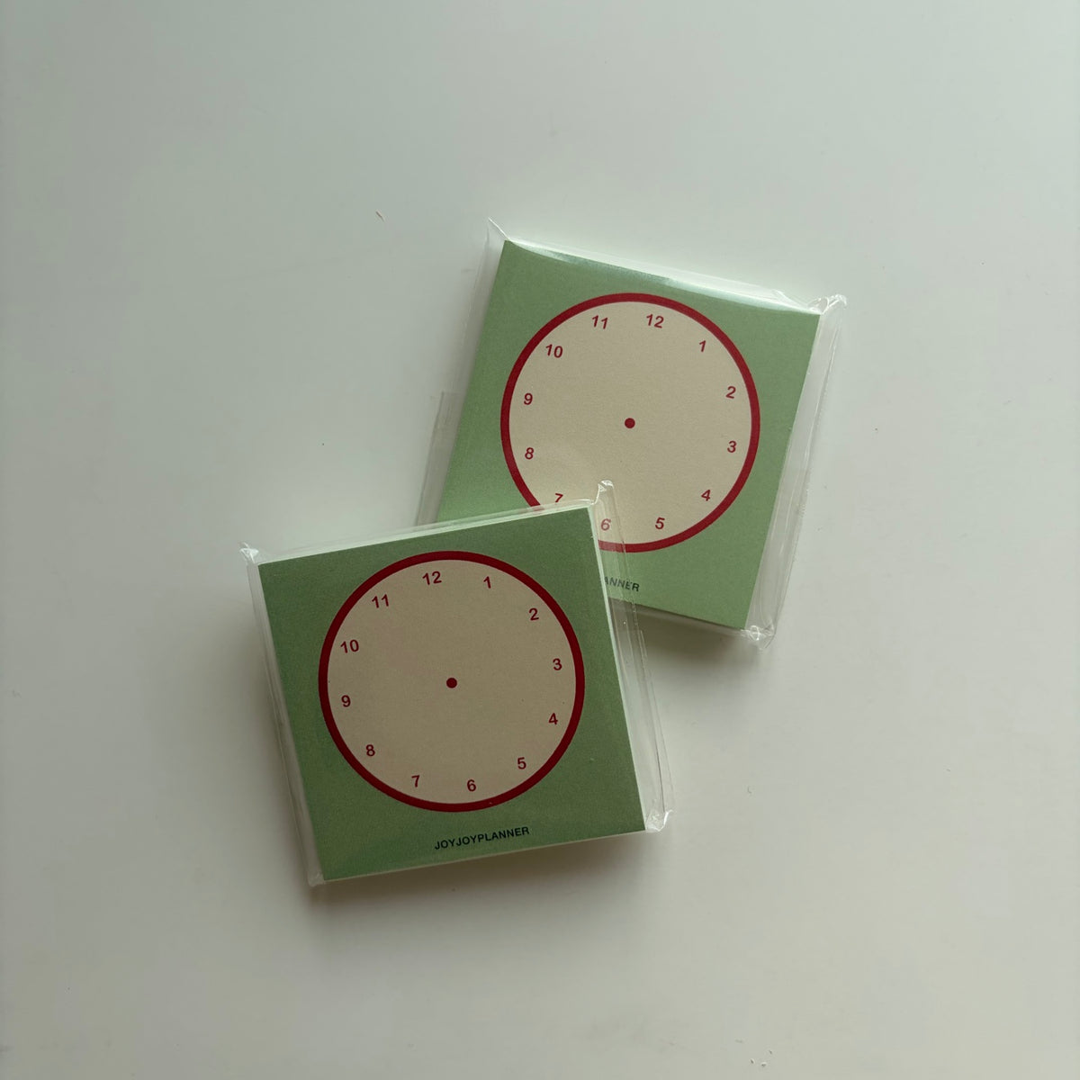 Real photo of two packaged Visual Time Tracker mini memo pads with 1–12 clock layouts