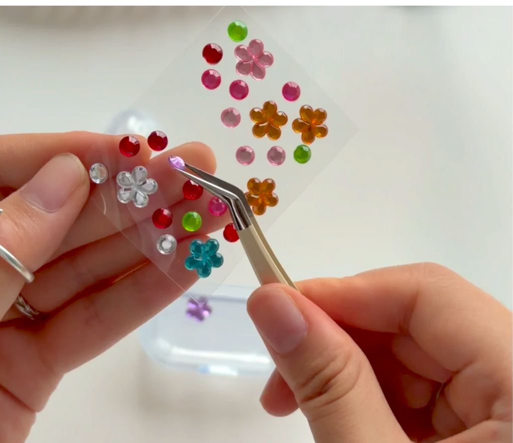 Close-up of a colorful Whimsy Gems sticker being lifted with tweezers for a DIY project