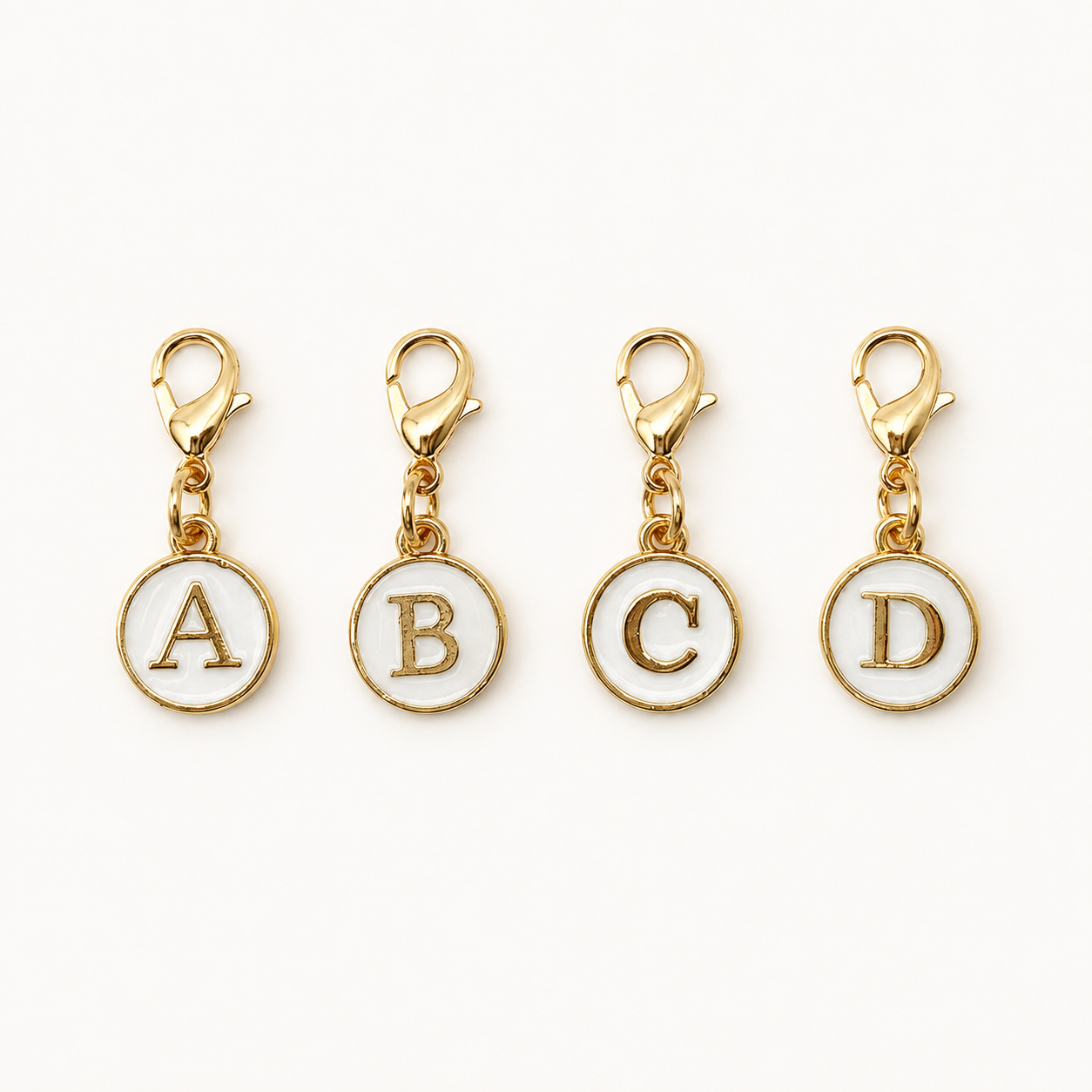 White and gold clip-on initial planner charms showing letters A, B, C, and D on a white background